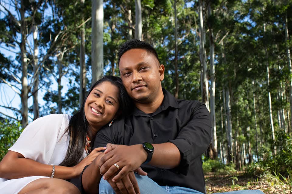Renesh and Chanelle sitting together in a sunlit forest