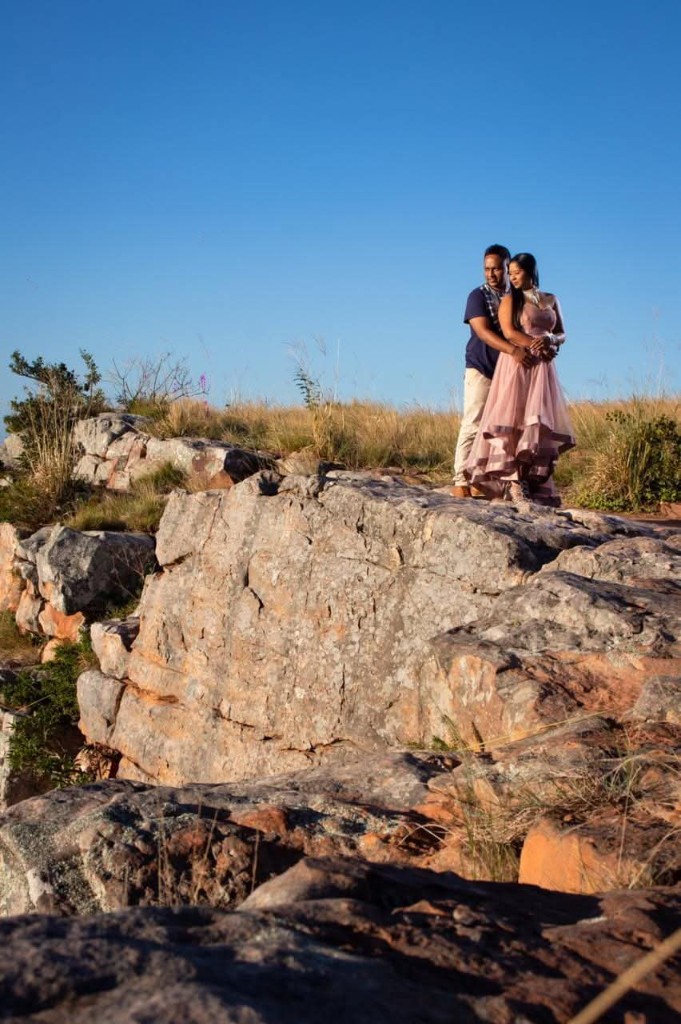 Renesh and Chanelle embracing on a rocky cliff at sunset